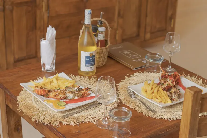 Grilled seafood and white wine laid for dinner on a carved wooden table