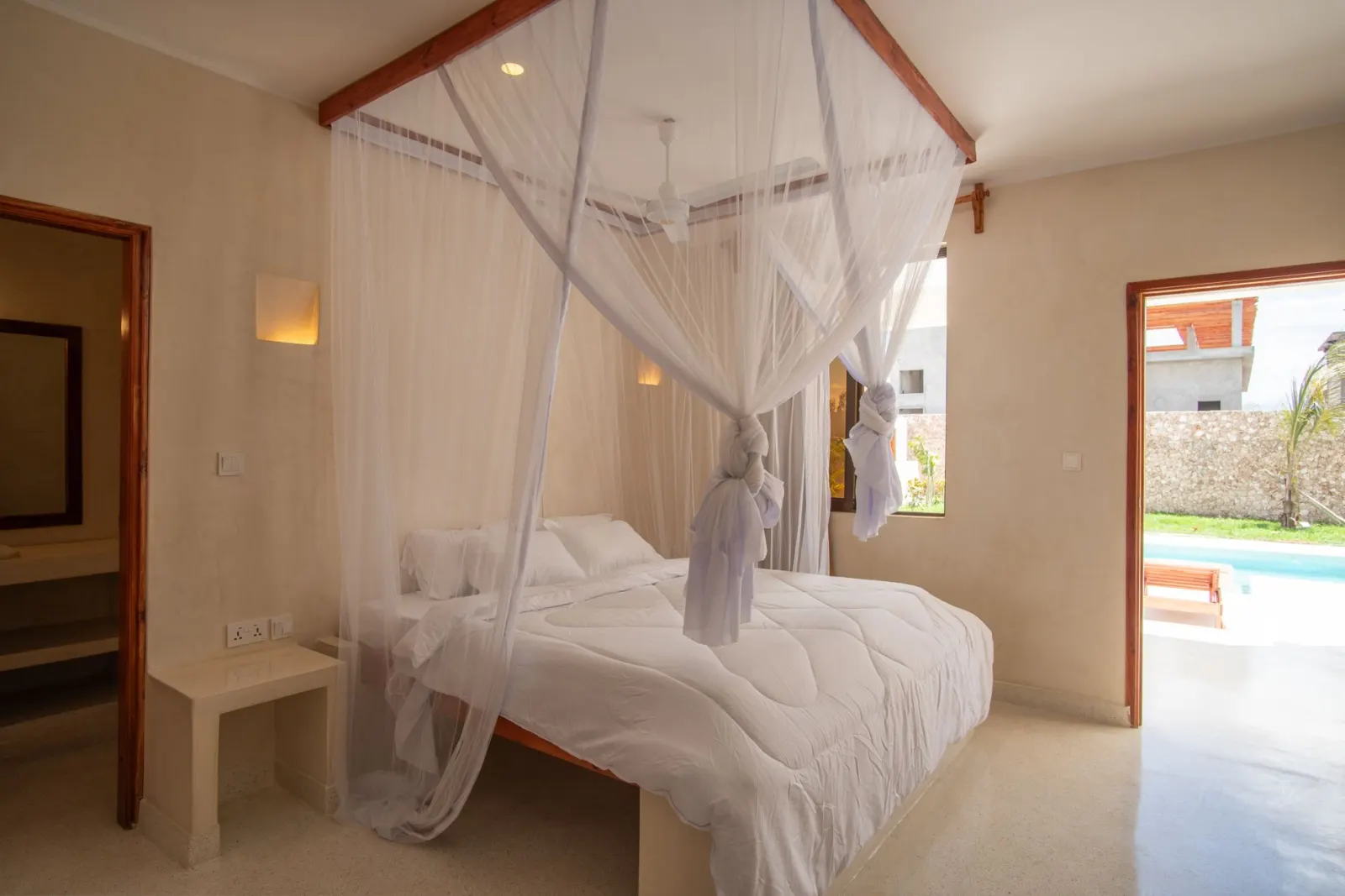A king-size bed under a mosquito net, the pool beyond